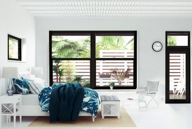 A bright and airy bedroom with white furniture, bedding and black windows