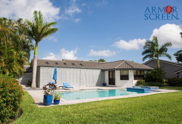 The exterior view of a home featuring a backyard pool with hurricane screen covering the patio area.