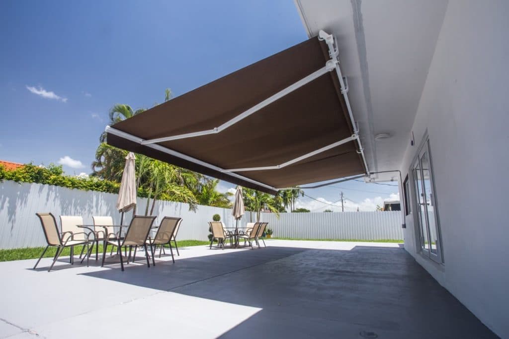 A backyard patio with outdoor furniture and a large retractable awning