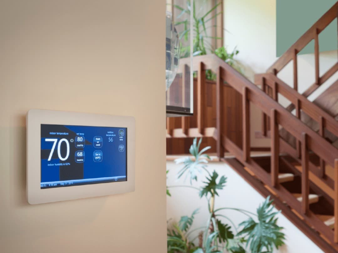 A digital thermostat mounted on a wall in a home.
