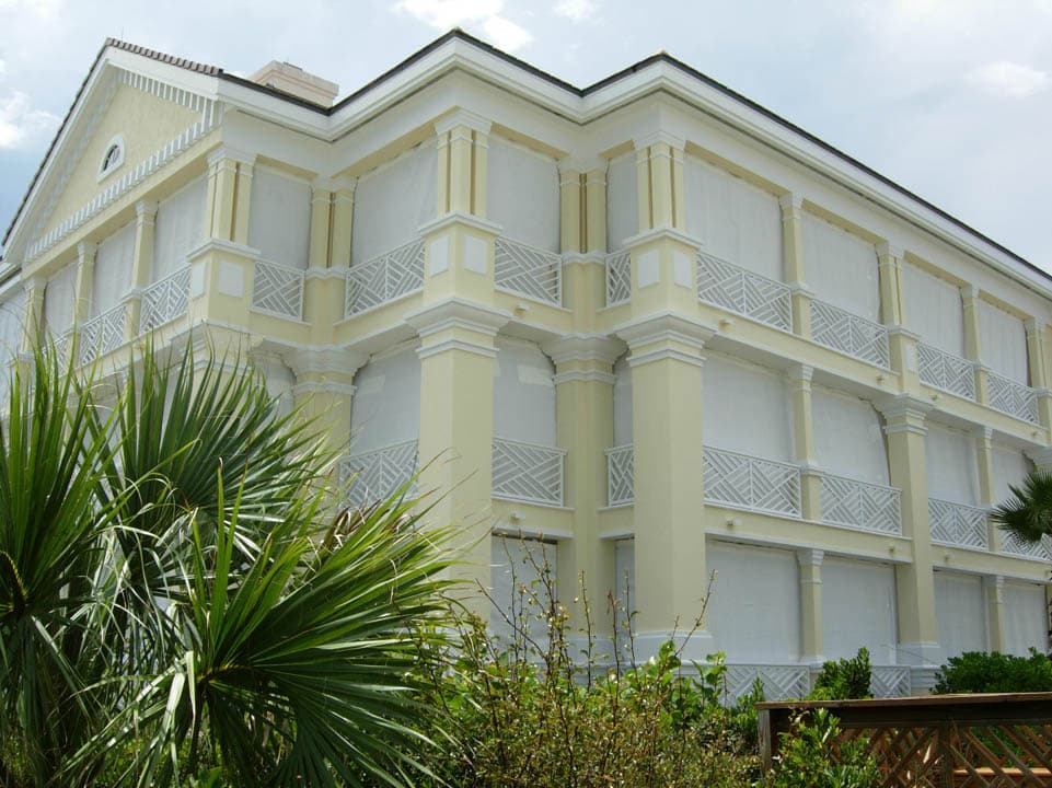 Multi story coastal condo building with hurricane fabric screens covering balconies and windows.