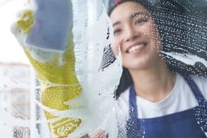 A person cleaning a window with soapy water and a sponge